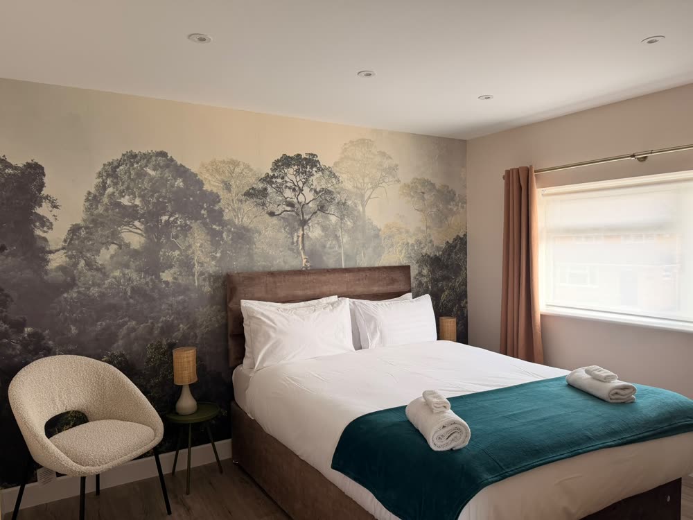 Bedroom with forest wall mural, fresh linen and folded towels