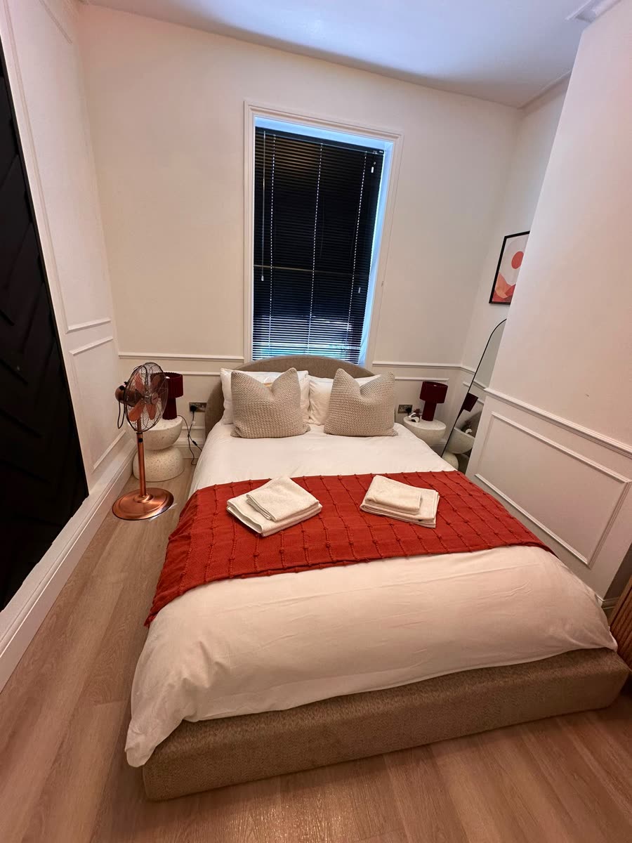Guest bedroom with red throw and towels laid out