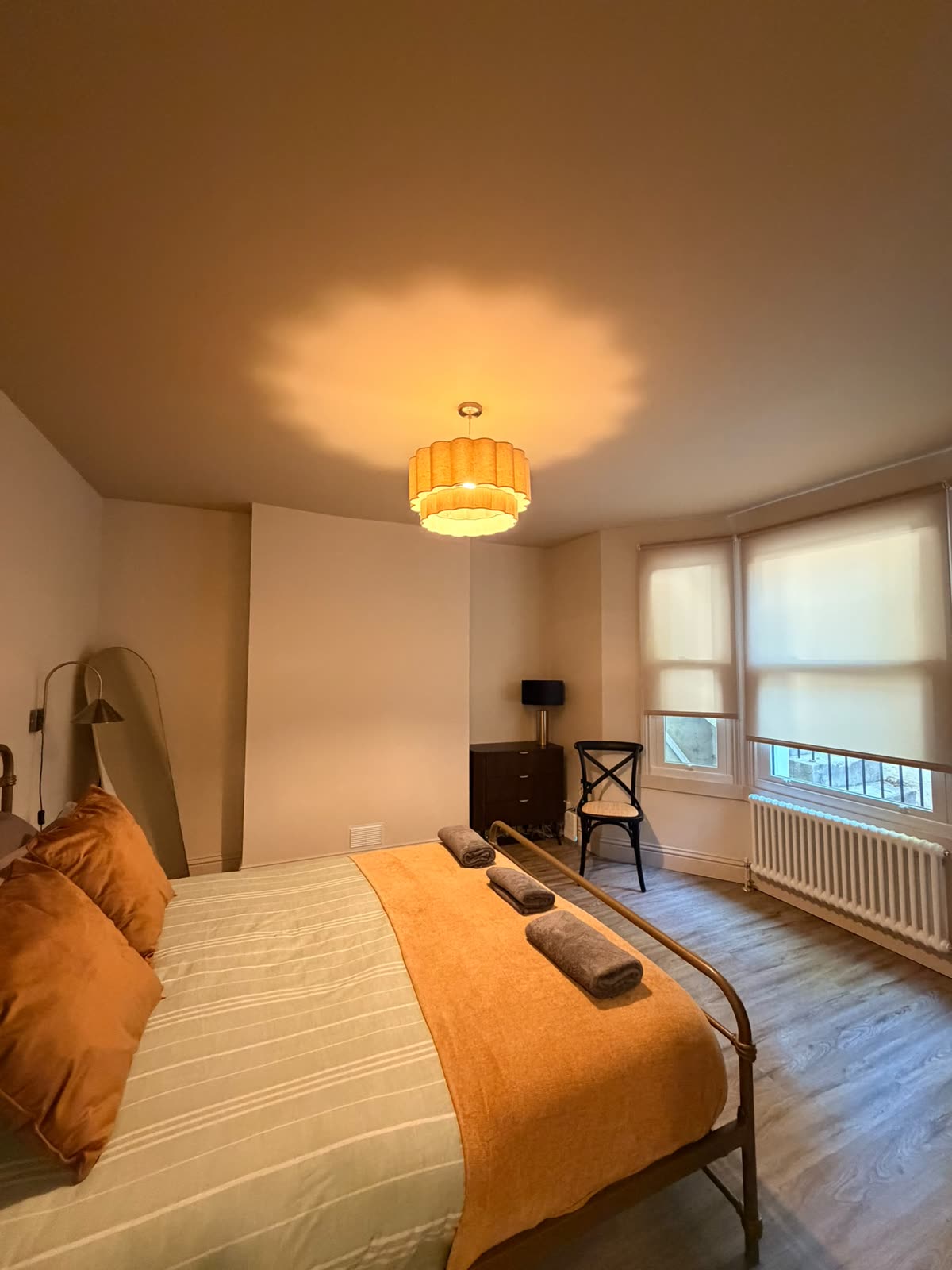Bedroom with warm lighting, made bed and rolled towels