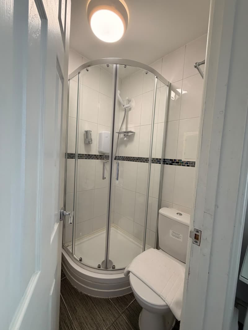 Shower room with gleaming glass enclosure, toilet and tiled floor