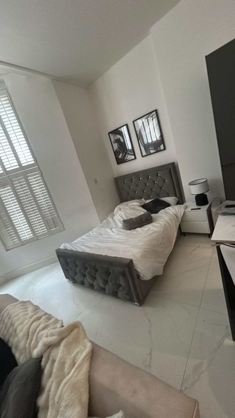 Studio bedroom with shutters, made bed and polished floor